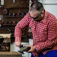 Workshop worker sawing some metal.